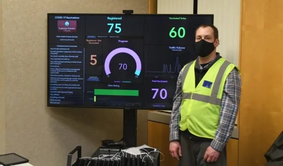 A Carlton County GIS Coordinator in front of the Esri dashboard showing the progress of the drive-through COVID-19 vaccine clinic